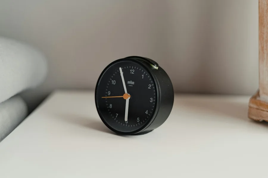 A small black analog clock in natural light.