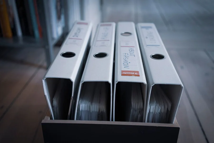 Document binders stored in a wooden file box.