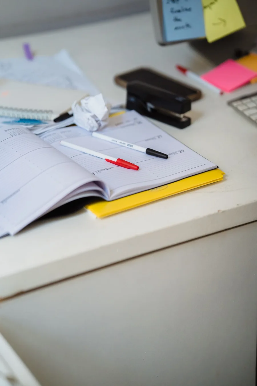 An open weekly planner with office supplies.